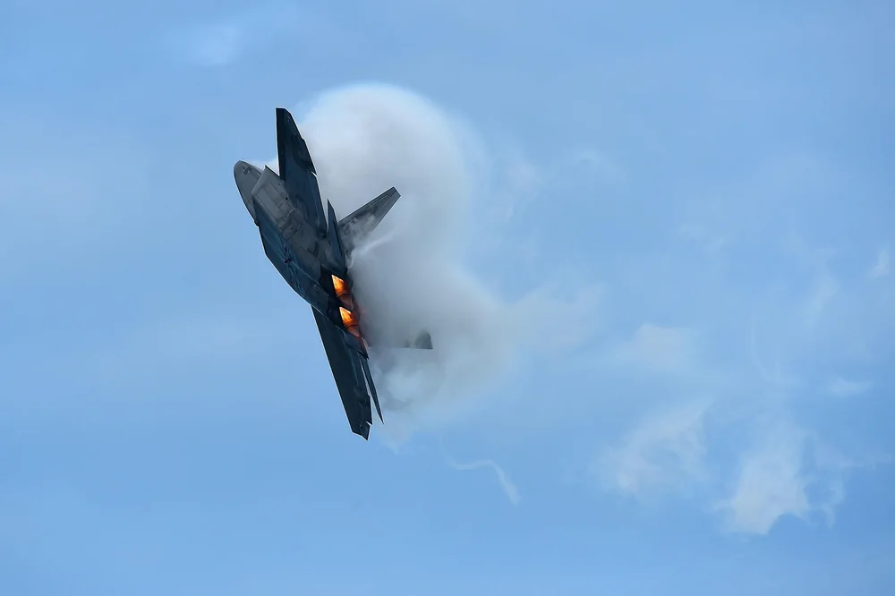 A real F-22 climbing through vapor with its afterburners lit